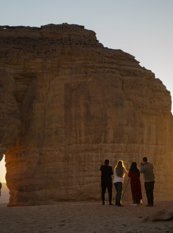 A group of adults capturing images of Elephant Rock at sunset